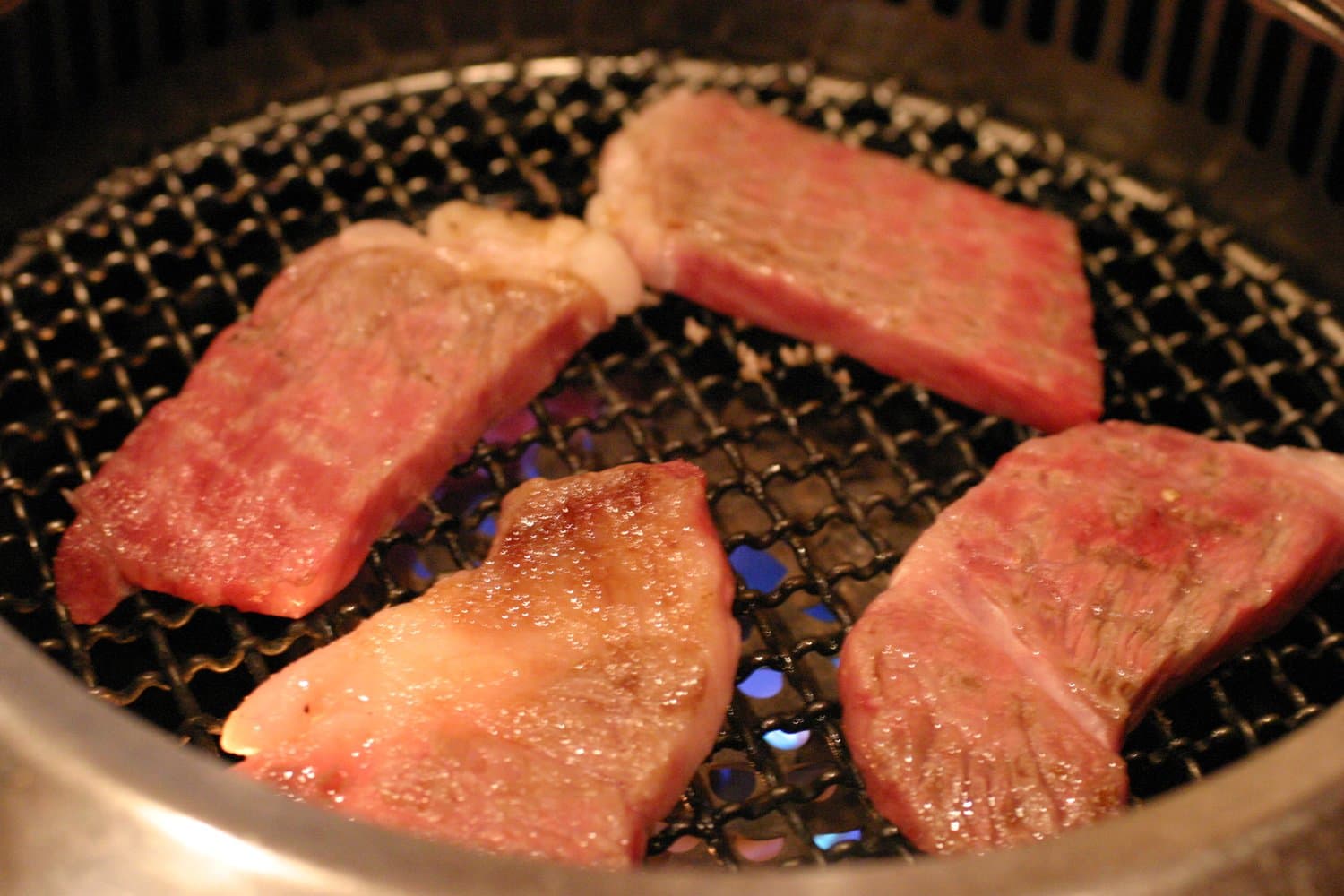 Marbled Joshu wagyu beef grilling over a tabletop charcoal grill