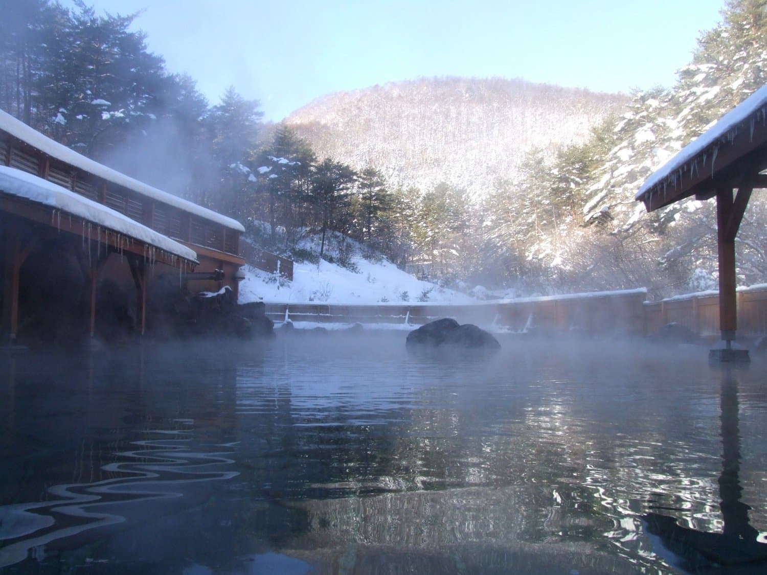 The Sainokawara Rotenburo open-air bath in winter, snow on the surrounding hills