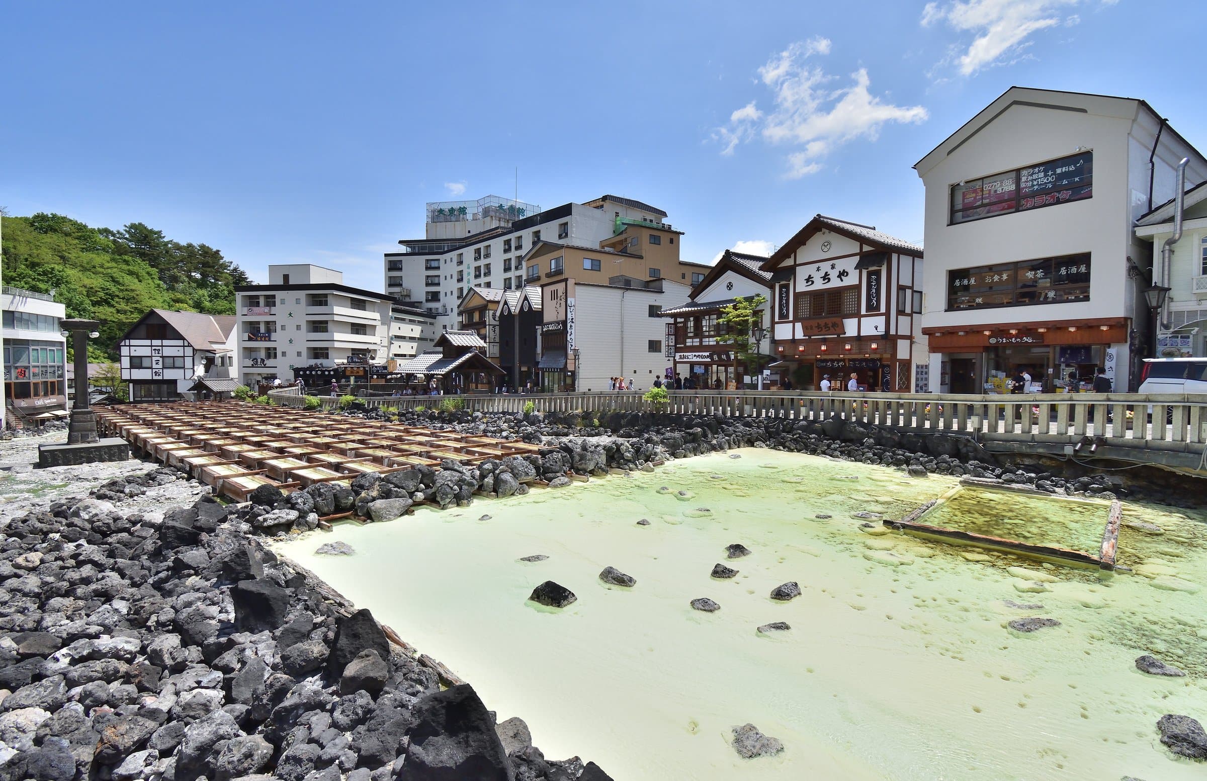The Yubatake hot-water field and its wooden cooling channels in the centre of Kusatsu under a blue sky